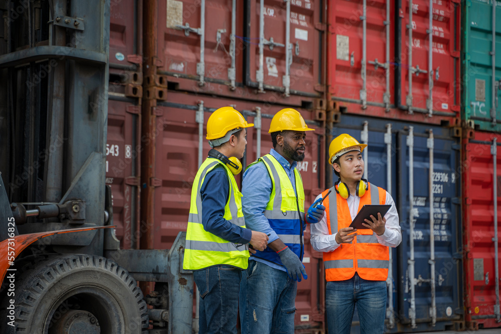 Three workers talk at an outdoor job site in the shipping industry.